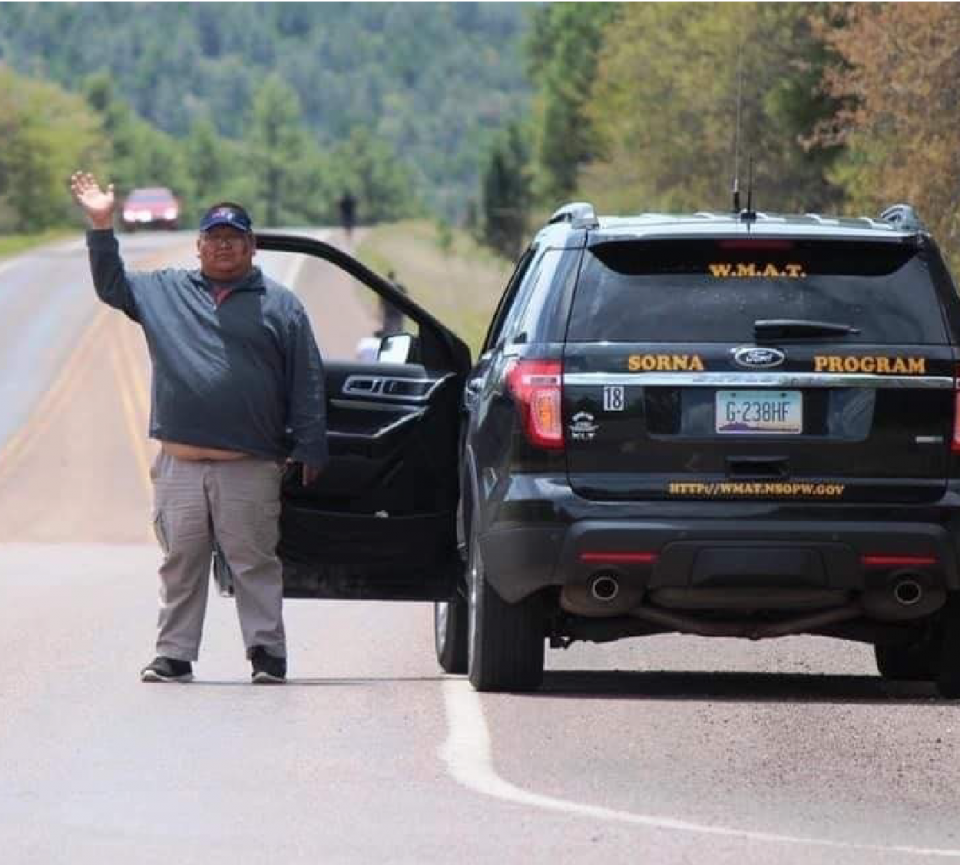 Elmer Lamson waves near a WMAT SORNA Program vehicle.