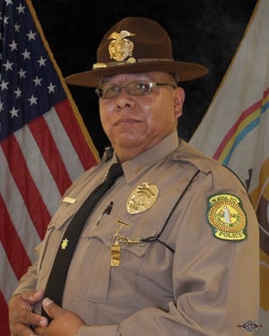 Officer Michael Lee Stands in front of an American flag in uniform.